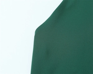 Texture macro détaillée du tissu de robe midi vert foncé montrant le tissage premium