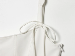 Detail of white blouse featuring adjustable bow shoulder straps and hidden side zipper