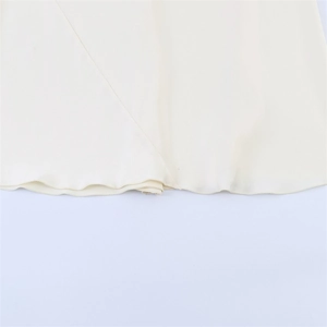 Detailed close-up of the finely stitched hem on a flowing cream-colored maxi dress
