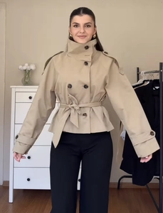 Detail of khaki double-breasted short trench coat with belt and shoulder straps