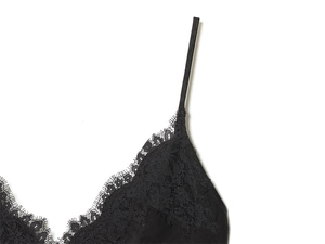 Macro detail of the fine eyelash floral lace and black strap on this chic women top