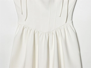 Detailed view of white pleated waist structure and delicate tiered fabric stitching