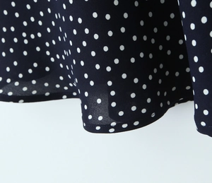 Detail shot of navy blue polka dot fabric with refined stitched hemline on dress