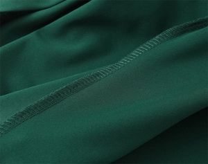 Vue macro détaillée du tissu vert foncé montrant le tissage fin et la couture surjet