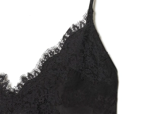 Detail of elegant black V-neck top showing delicate eyelash lace trim and silky fabric