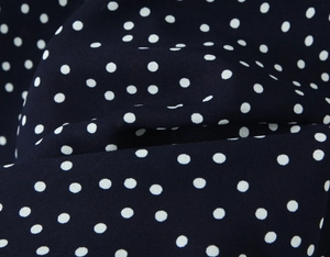 Detail shot of navy blue fabric with white polka dots for a chic summer dress