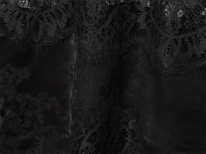 Detail of elegant black eyelash lace fabric with textured satin base on long top