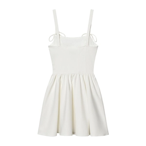 Women's white sleeveless mini dress with bow detail and pleated skirt on a plain background