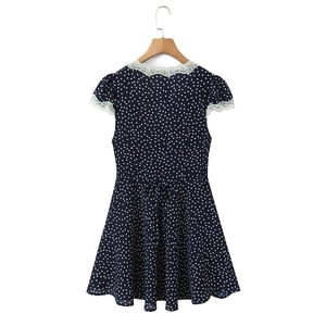 Detailed view of white lace trim on a navy polka dot V-neck dress and waist drawstring