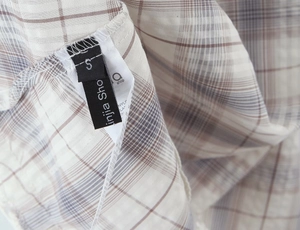 Gros plan sur l'étiquette taille S et instructions de lavage de la robe à carreaux