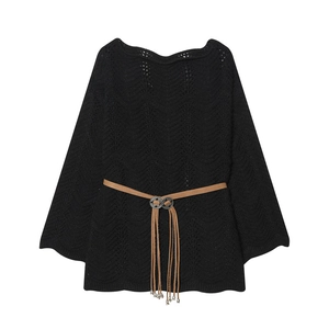 Détail du haut en tricot noir avec texture ajourée ondulée et ceinture à pompons