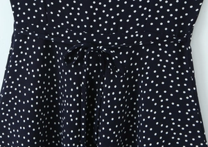 Detailed macro view of the navy blue polka dot dress with tied waist bow and fabric texture