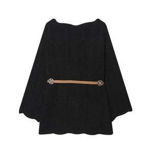 Détail d'un pull noir ample avec une ceinture marron élégante et une bordure festonnée