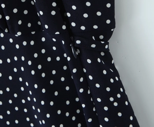 Detail view of hidden side zipper and white polka dot print on navy blue dress