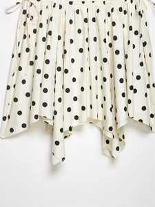Détail d'une jupe asymétrique à pois montrant le tissu léger et l'ourlet drapé