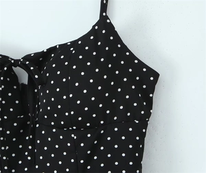 Detail of black polka dot dress featuring a front bow tie and spaghetti straps