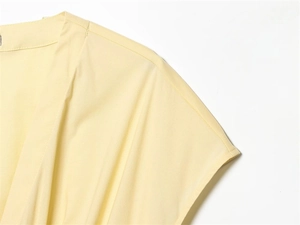 Close-up of shoulder stitching on a light yellow poplin dress with fine fabric texture