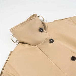 Detail view of khaki trench coat featuring resin buttons, shoulder tabs, and high collar