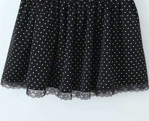 Detail of black polka dot dress featuring elegant lace trim and soft pleated fabric textures