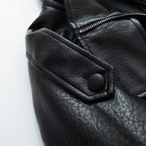 Detail of black faux leather jacket with epaulet button and silver metal zipper texture