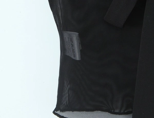 Détail du tissu en maille noire semi-transparente avec un ruban décoratif à texture fine