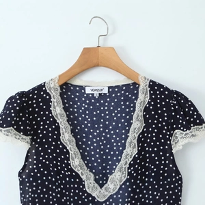 Navy blue V-neck polka dot dress with white lace trim and short sleeves on a wooden hanger
