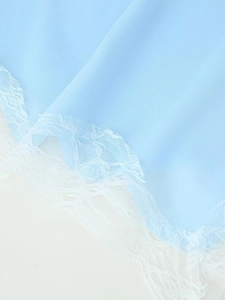 Close-up of light blue chiffon fabric with intricate white lace floral embroidery edge