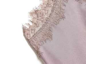 Detailaufnahme von Wimpernspitze und glattem Seidenstoff an einem lila Kleid