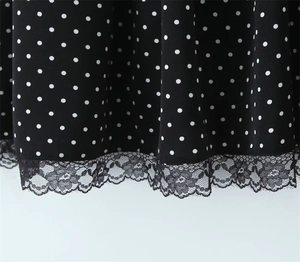 Detail showing white polka dot fabric with black floral lace trim on the garment hem