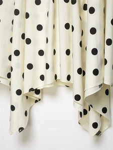 Vue détaillée du motif à pois sur un tissu crème fluide avec un ourlet élégant