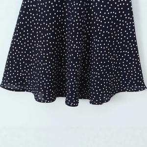 Close-up of lightweight black and white polka dot chiffon dress hemline with wavy pleats