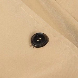 Macro detail of khaki trench coat featuring tortoise resin button and twill fabric texture