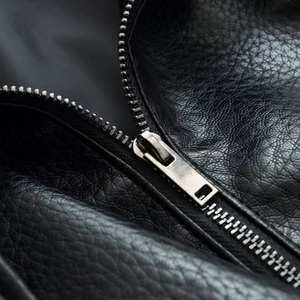Detailed close-up of premium black leather texture with a durable silver metal zipper