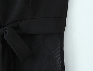Détail du haut noir avec empiècement en résille et nœud de serrage latéral