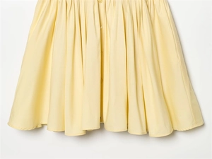 Close-up of a pale yellow poplin mini dress featuring gathered details and button-down front