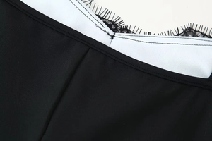 Dettaglio dello scollo in pizzo bianco e nero con delicate rifiniture a ciglia