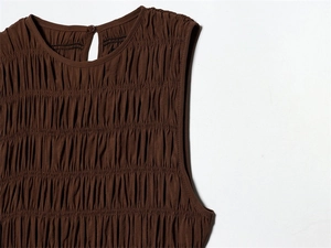 Detailed view of smocking texture on a dark brown sleeveless dress with keyhole button closure