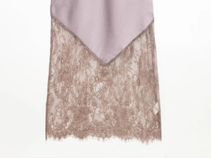 Detail von mauvefarbenem Satin mit zarter Wimpernspitze am Saum eines Sommerkleides