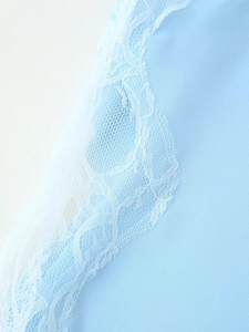 Macro detail of light blue fabric with intricate white lace trim and delicate mesh texture