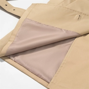 Detailed close-up of khaki trench coat fabric stitching with smooth inner lining and eyelet