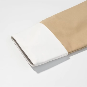 Detailed view of khaki and white color block cuffs on a stylish spring trench coat
