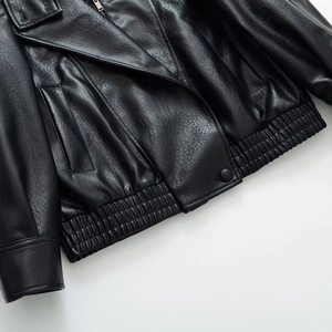 Detail of faux leather jacket featuring lychee texture and elastic pleated hemline