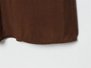 Close-up of double-stitched hem on dark brown satin fabric showing high-quality sewing