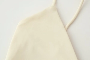Detail showing high-elastic ribbed knit fabric and thin spaghetti straps on beige dress