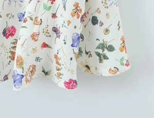 Close-up of floral print fabric with red and purple flowers on a white dress hem