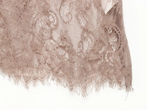 Makro-Detail von zarter floraler Wimpernspitze in Vintage-Mauve für Damenkleider
