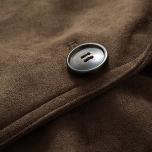 Close-up of brown suede jacket texture with a detailed dark resin button and stitching