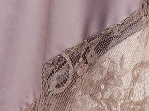 Detail aus lila Satinstoff mit aufwendigem dunkelbraunem Wimpernspitzenbesatz
