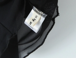 Détail de l'étiquette d'entretien et taille S sur la jupe en résille à pois