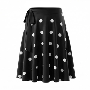 Détail d'une jupe mi-longue à pois noirs avec un nœud latéral et un ourlet drapé